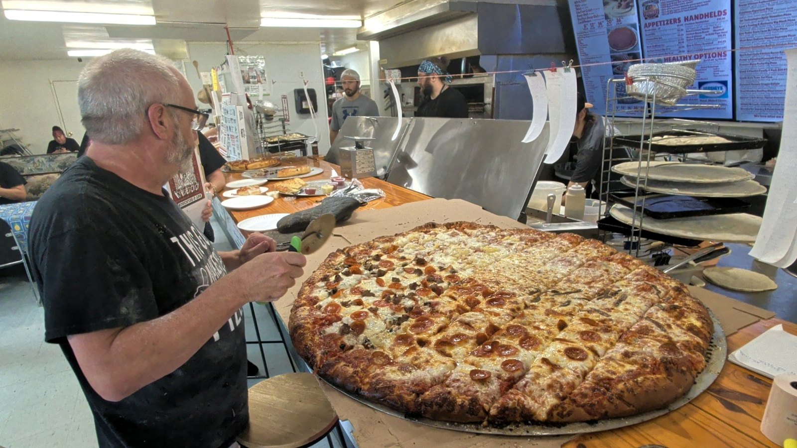 Freshieez staff cutting the finished 36 inch Tiny pizza during the September GastroMob kickoff